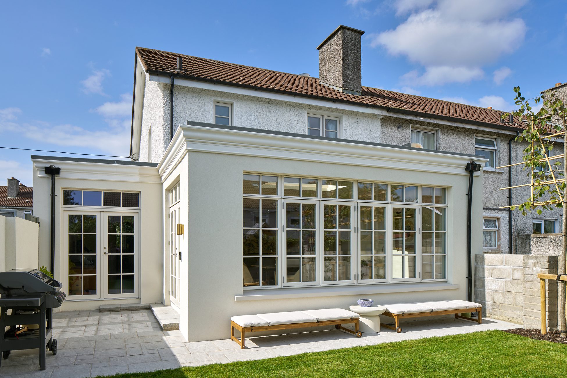 A Shomera house extension with a glazed garden room and bi-fold doors, seen from the lawn