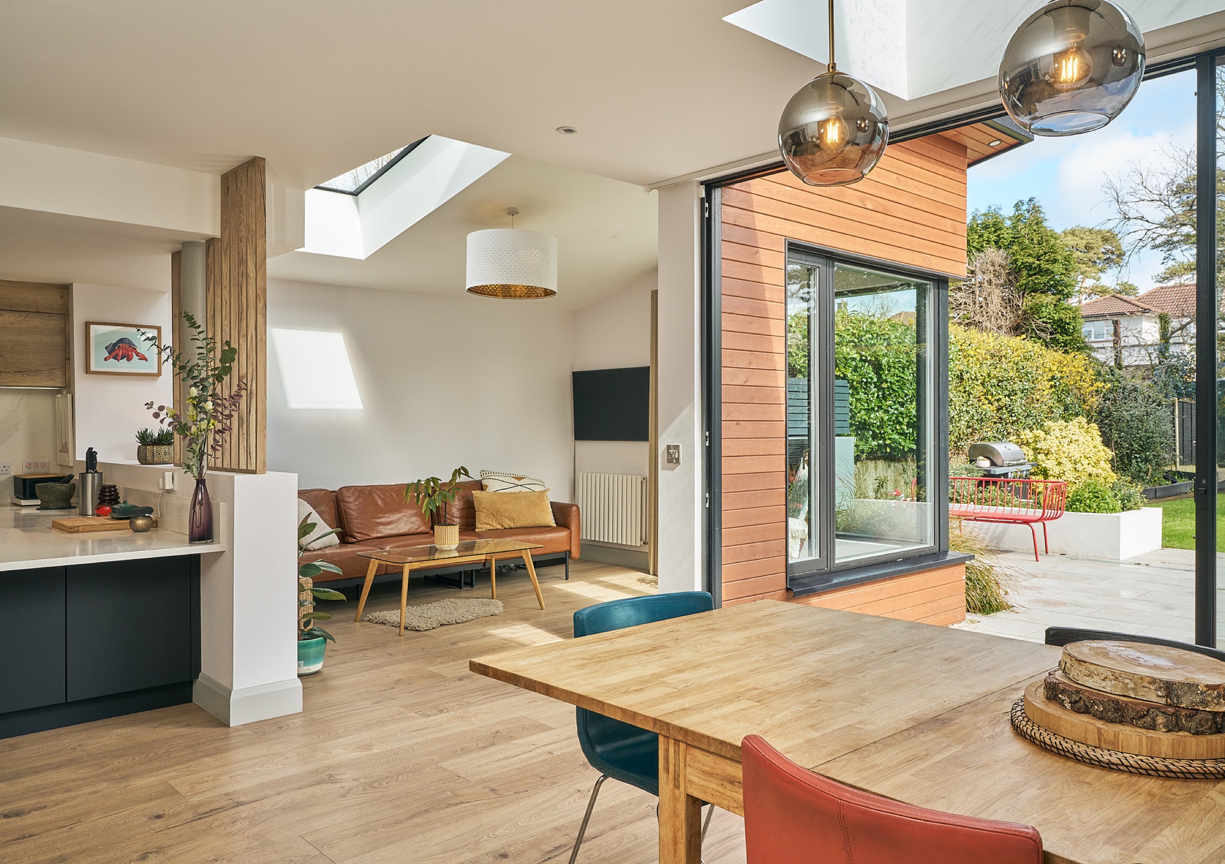 The open-plan living and dining room of a Shomera house extension, with a rooflight, timber floor and full-height glazing onto the garden